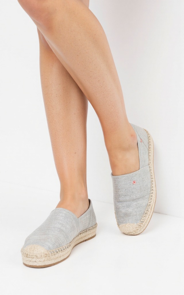 A female model wearing espadrilles, against a white background, with a close   up of the feet